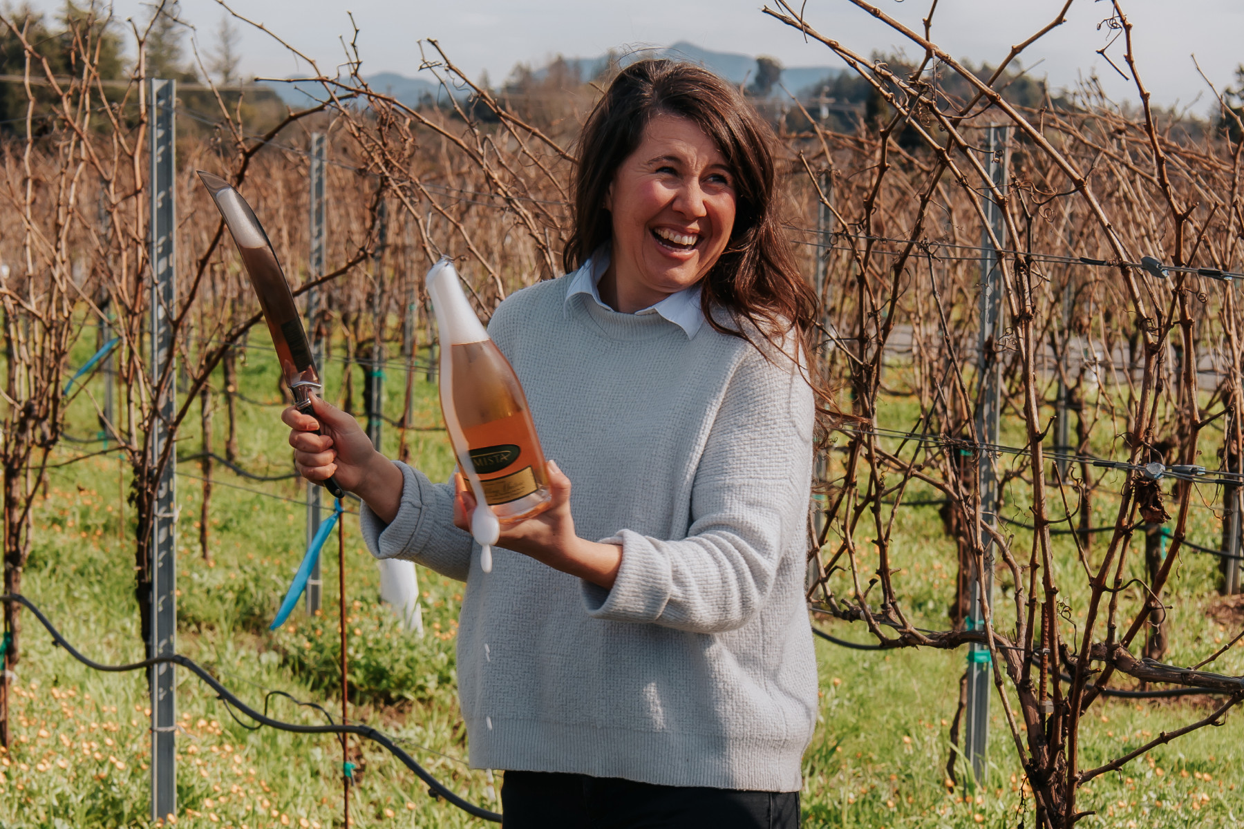 Ashley Herzberg Amista Winemaker with Bottle of Sparkling Wine in Vineyard