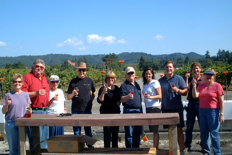Owners and Friends of Amista Vineyards Standing in the Vineyards with a Glass of Wine