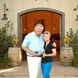 Amista Vineyards Proprietors, Mike and Vicky standing in front of their Tasting Room with glasses of Wine - Healdsburg, California