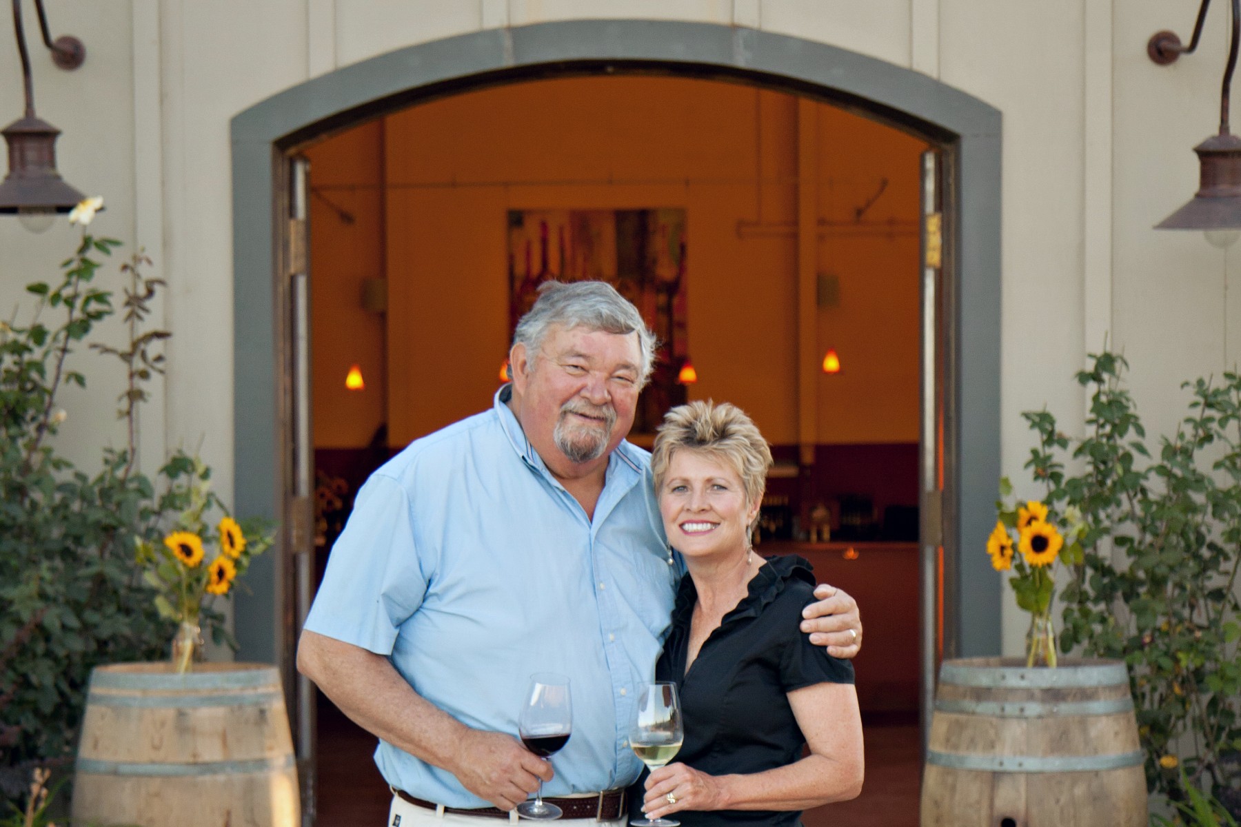 Mike & Vicky Farrow, Proprietors in Front of Amista Vineyards with Wine in Hand